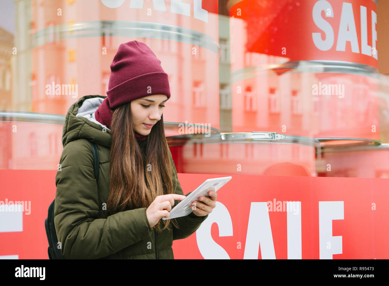 The girl at the storefront with a sale. Time of off-season and winter sales. Stock Photo