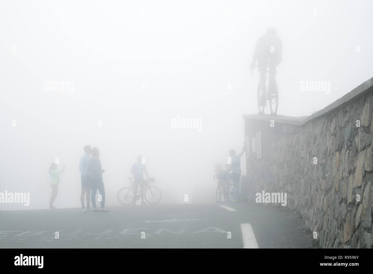 Tourists watching the statue for Tour de France cyclist Octave Lapize at the Col du Tourmalet in thick mist in the Pyrenees, France Stock Photo