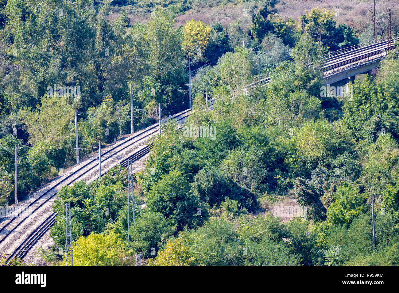 Diagonal double railway tracks crossing a forest, high angle view from above near the train station of Karlukovo, Northern Bulgaria in a sunny autumn  Stock Photo