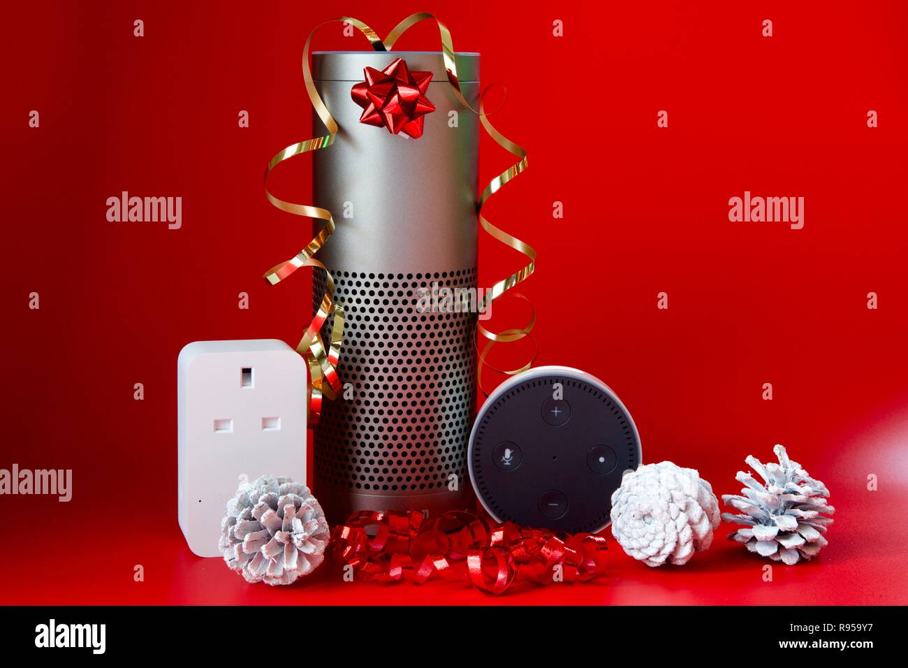 Amazon Echo, Echo Dot and Smart Plug with Christmas decorations on a red background Stock Photo