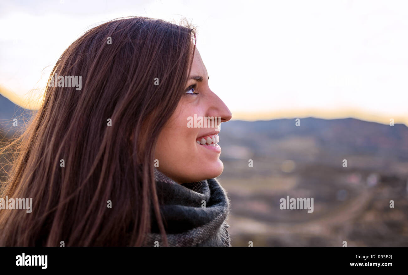 Smiling woman portrait side view. Young caucasian Spanish girl against agriculture fields. Freedom in nature. Stock Photo