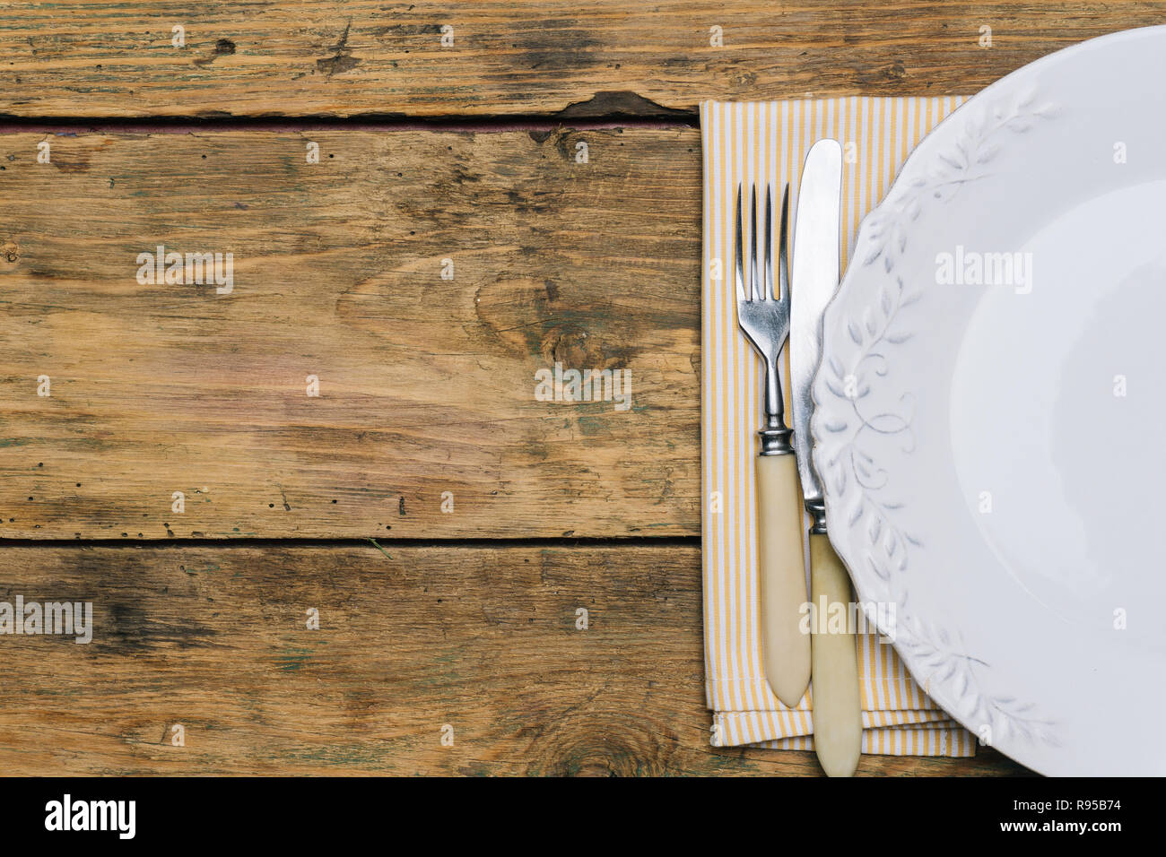 Empty white rustic plate on old wooden background with knife, fork and ...