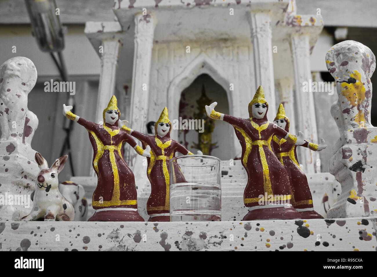 This unique photo shows red golden ceramic figures standing in front of a small Buddhist temple. The picture was taken in Thailand Stock Photo