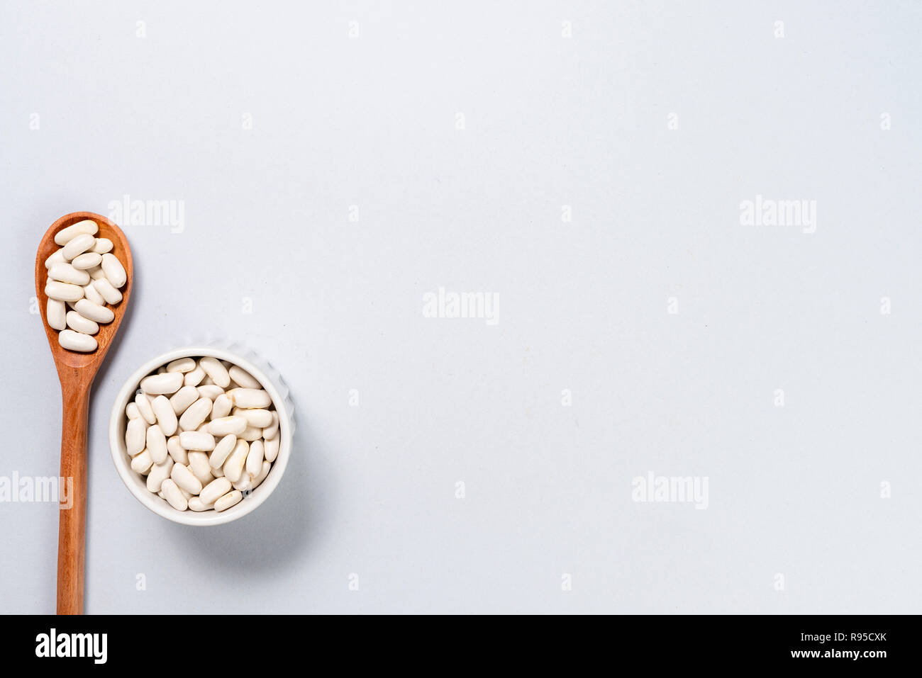 Wooden spoon and pot with white beans. Background with space for text ...