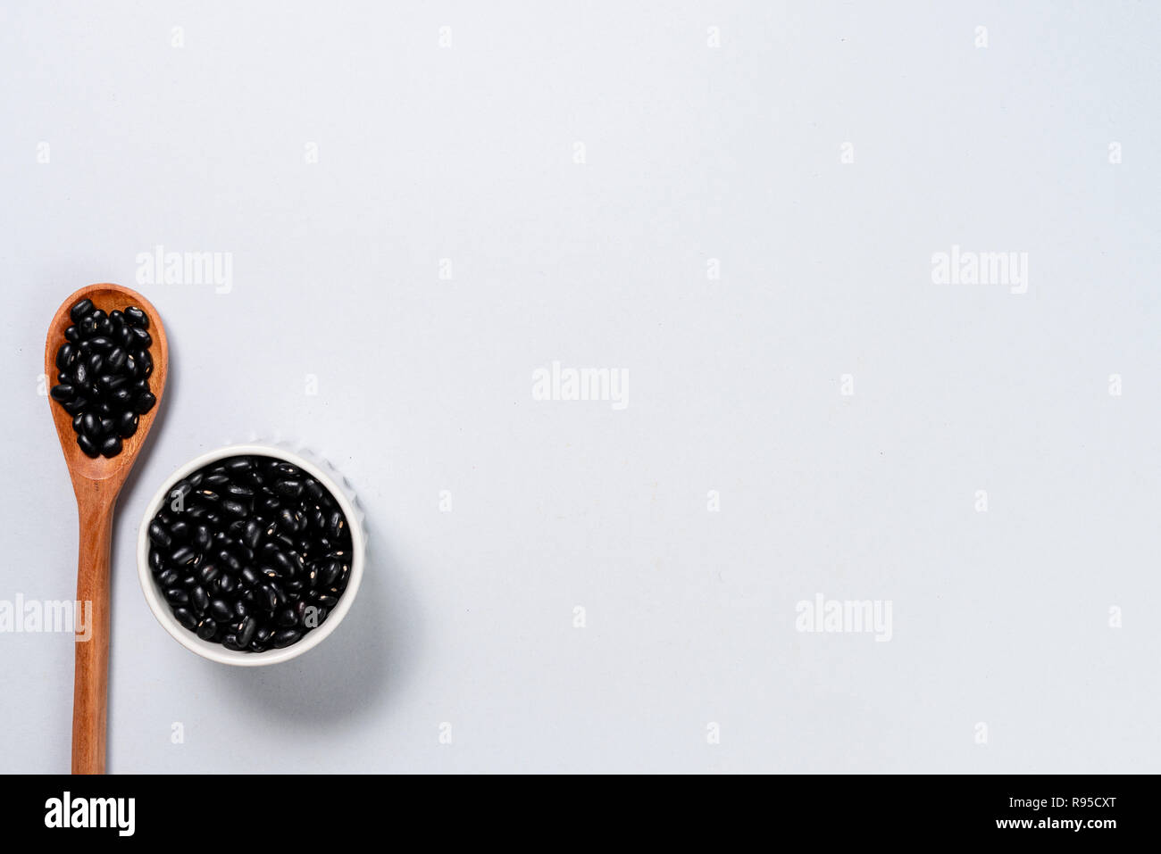 Wooden spoon and pot with black beans. Background with space for text ...