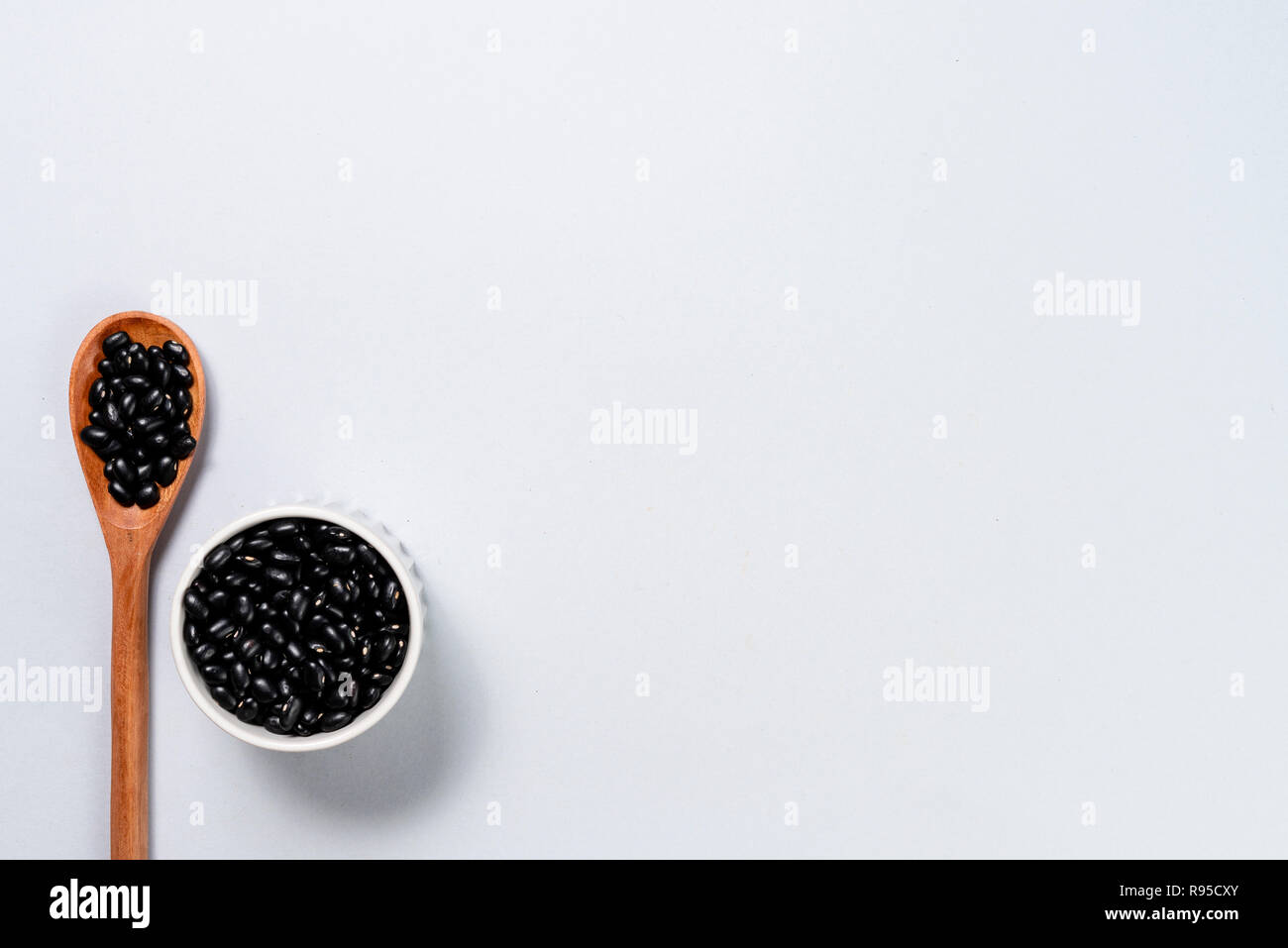 Wooden spoon and pot with black beans. Background with space for text ...