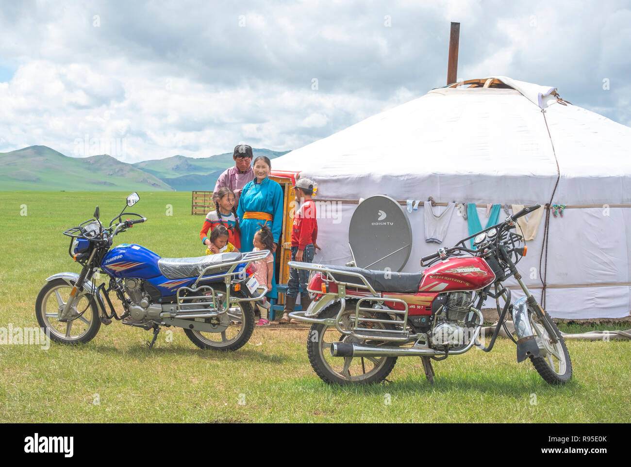 Mongolian nomad family posing next to their yurt known as ger and their robust motorbikes in the during summer. Stock Photo