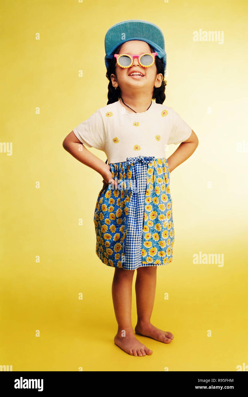 Girl wearing cap, fancy goggles, standing on yellow background Stock