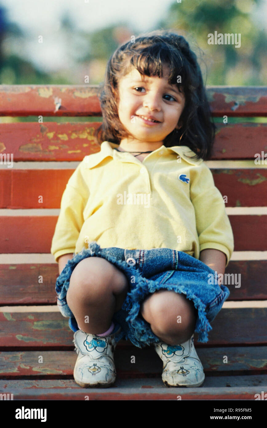 Baby girl child in blue jeans and yellow tshirt Stock Photo - Alamy