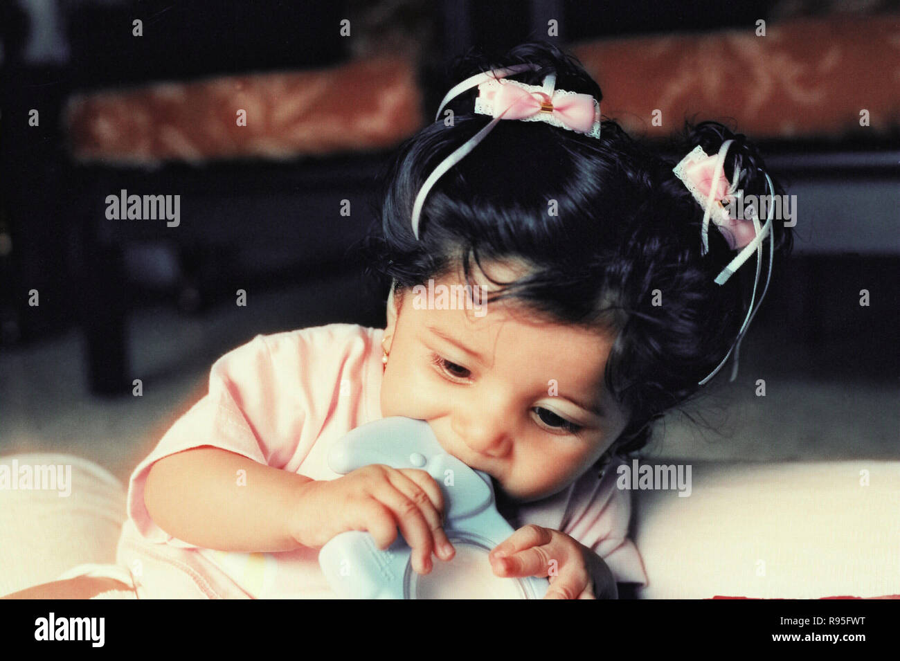 Baby girl sitting biting plastic toy - MR Stock Photo