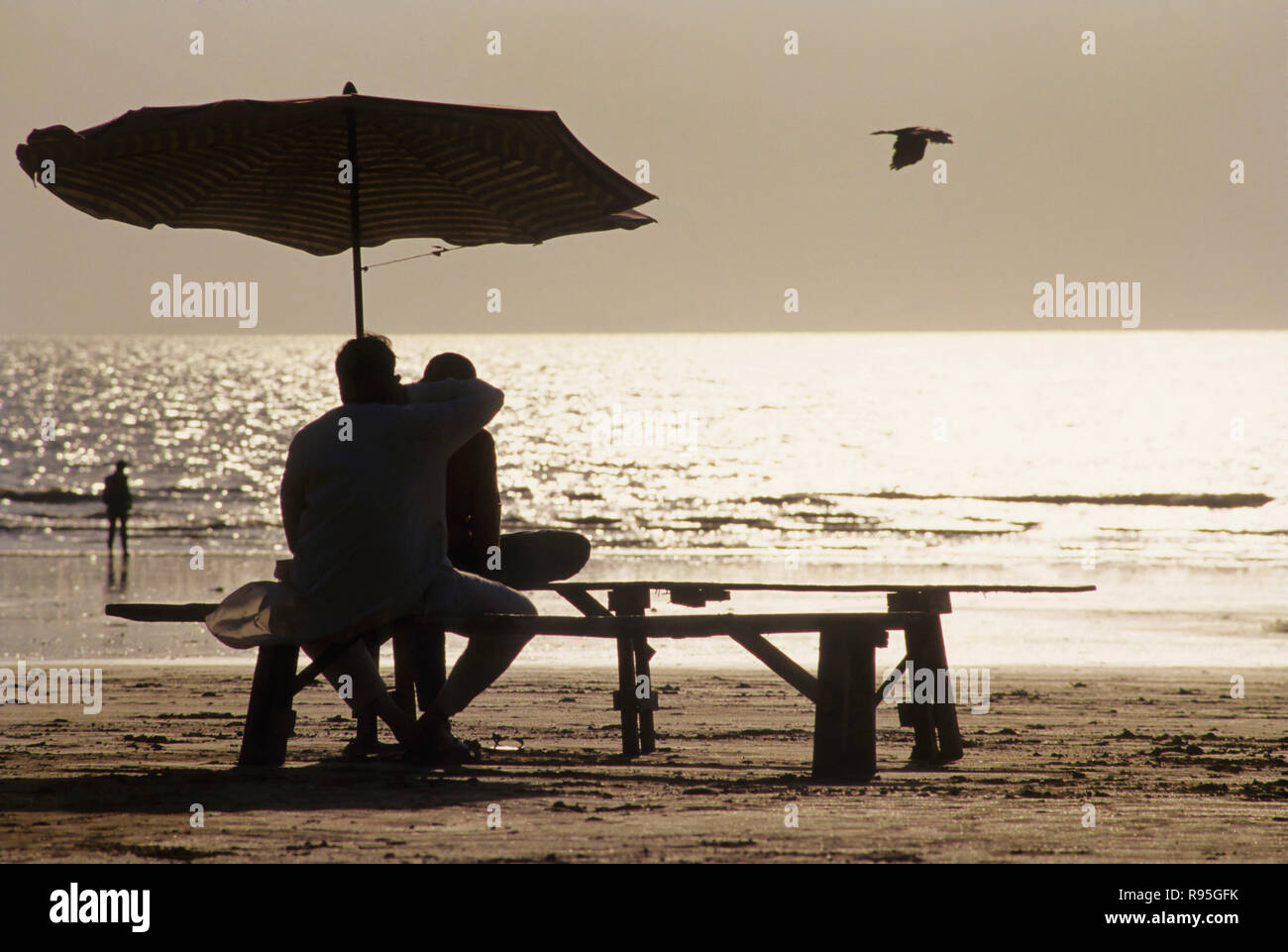 Couple sitting below umbrella, Juhu beach, Bombay, Mumbai, Maharashtra