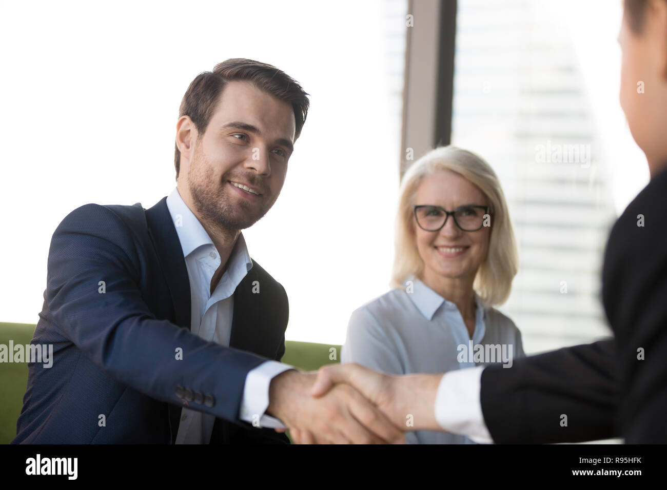 Handsome confident businessman shaking hands with client Stock Photo