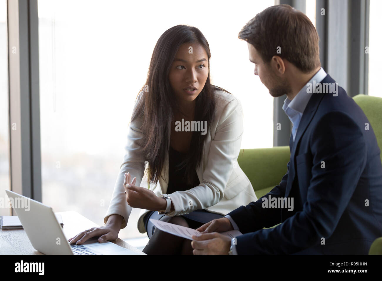 Asian caucasian colleagues sitting on couch discussing solve bus Stock Photo
