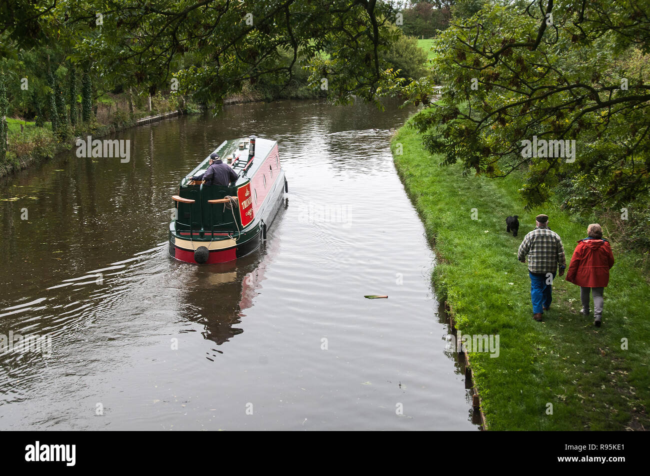 Around the UK Two walkers with their dog being passed by a canal