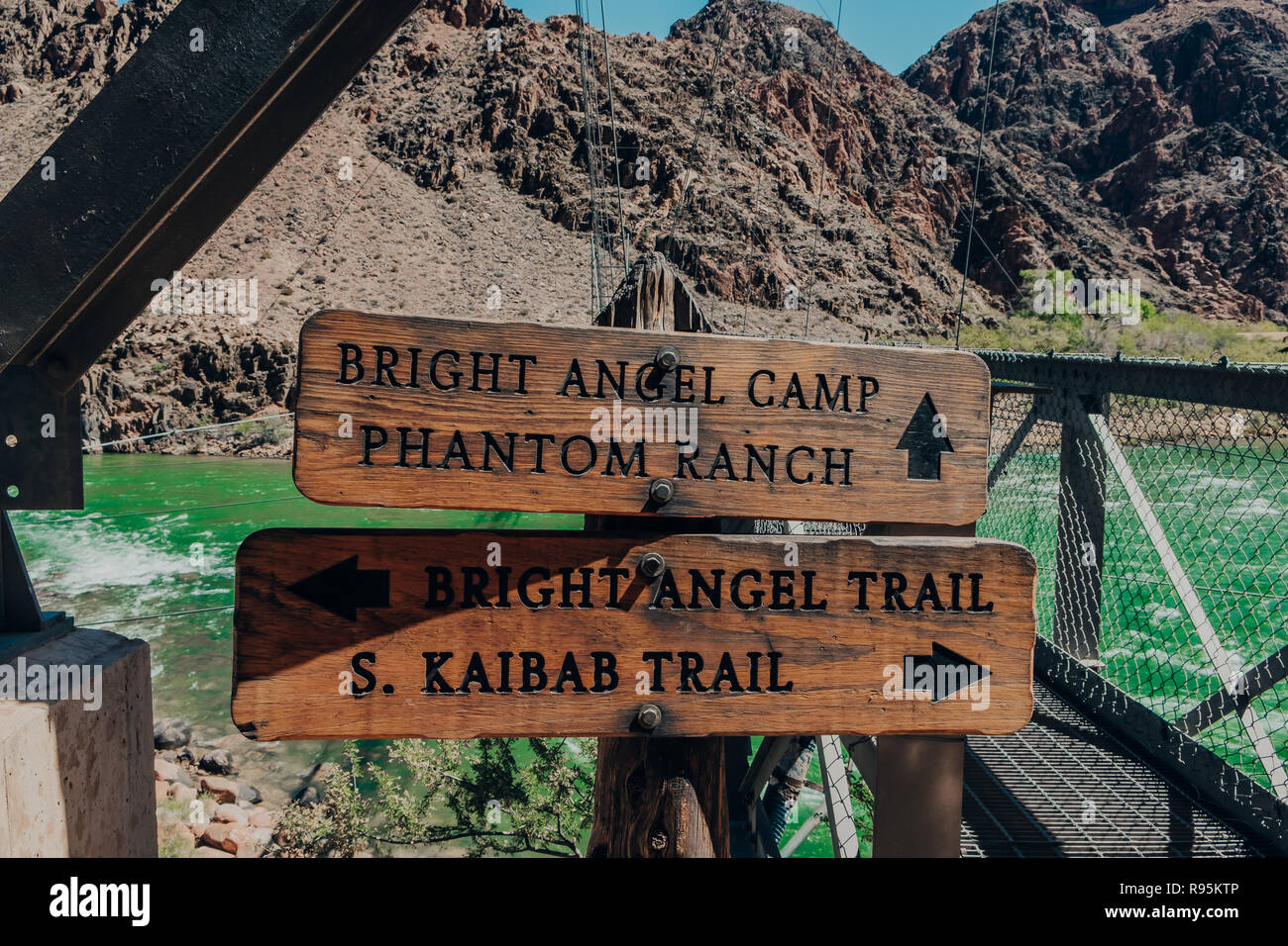 A couple of wooden trail signs on the Bright Angel Bridge by the green Colorado River in the Grand Canyon at Grand Canyon National Park in Arizona, US Stock Photo