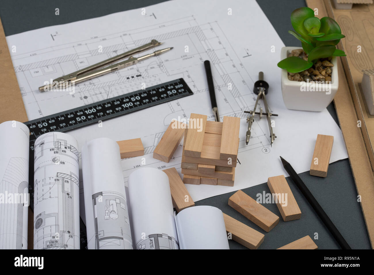 Workplace of architect - model house from wooden blocks, construction drawings, engineering tools on grey background Stock Photo