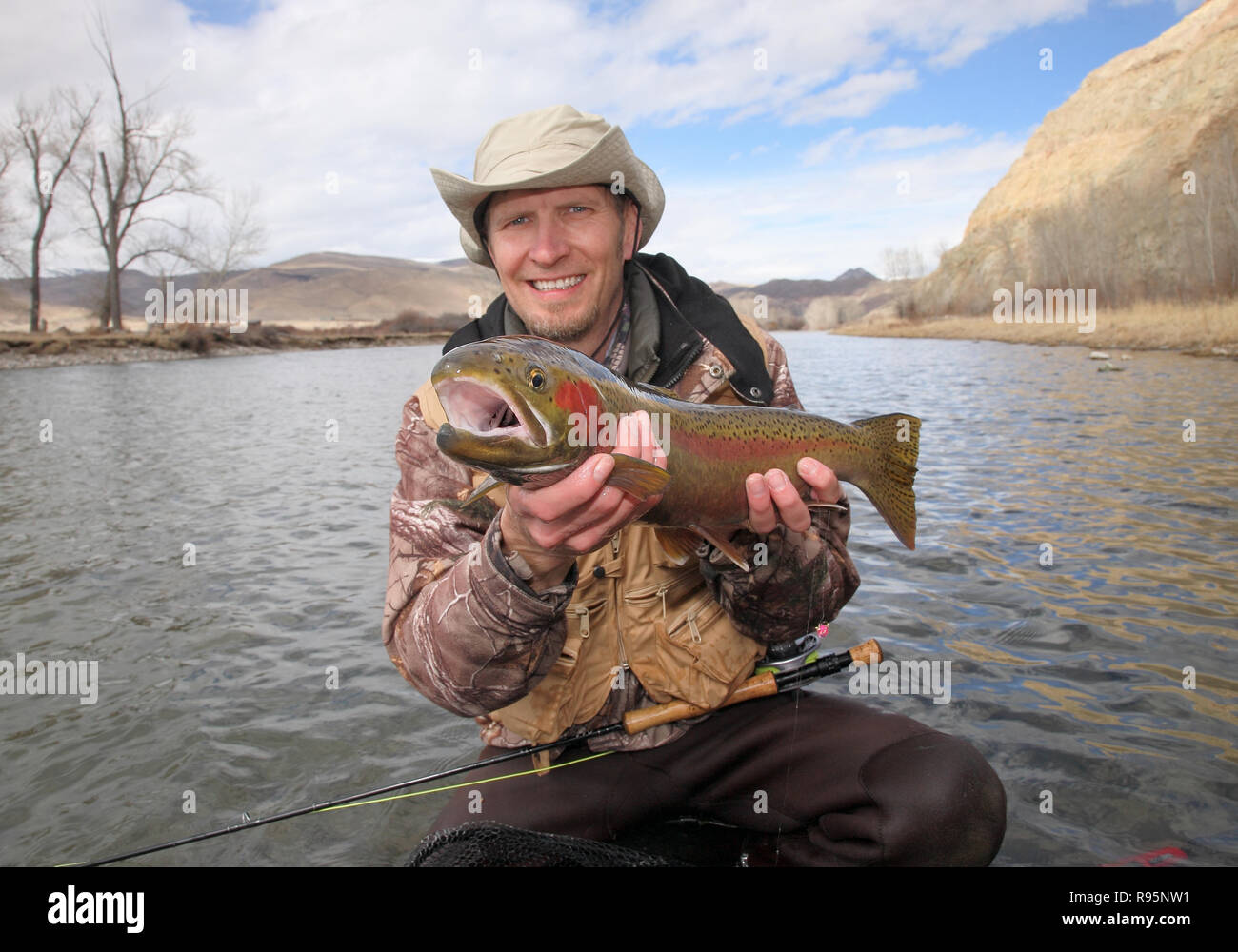 Happy fly fisherman holding large steelhead trout Stock Photo