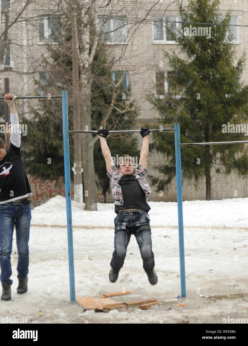 Kovrov, Russia. 4 April 2013. Teens is engaged in discipline gimbarr on a horizontal bar in the courtyard of a multi-storey residential building Stock Photo