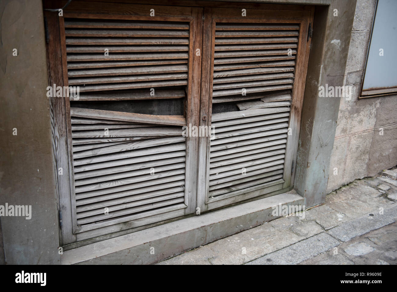 Closeup of a broken and old wooden door is seen on this picture. The door is pretty old and is broken. The old buildiing wall is also seen here. Stock Photo