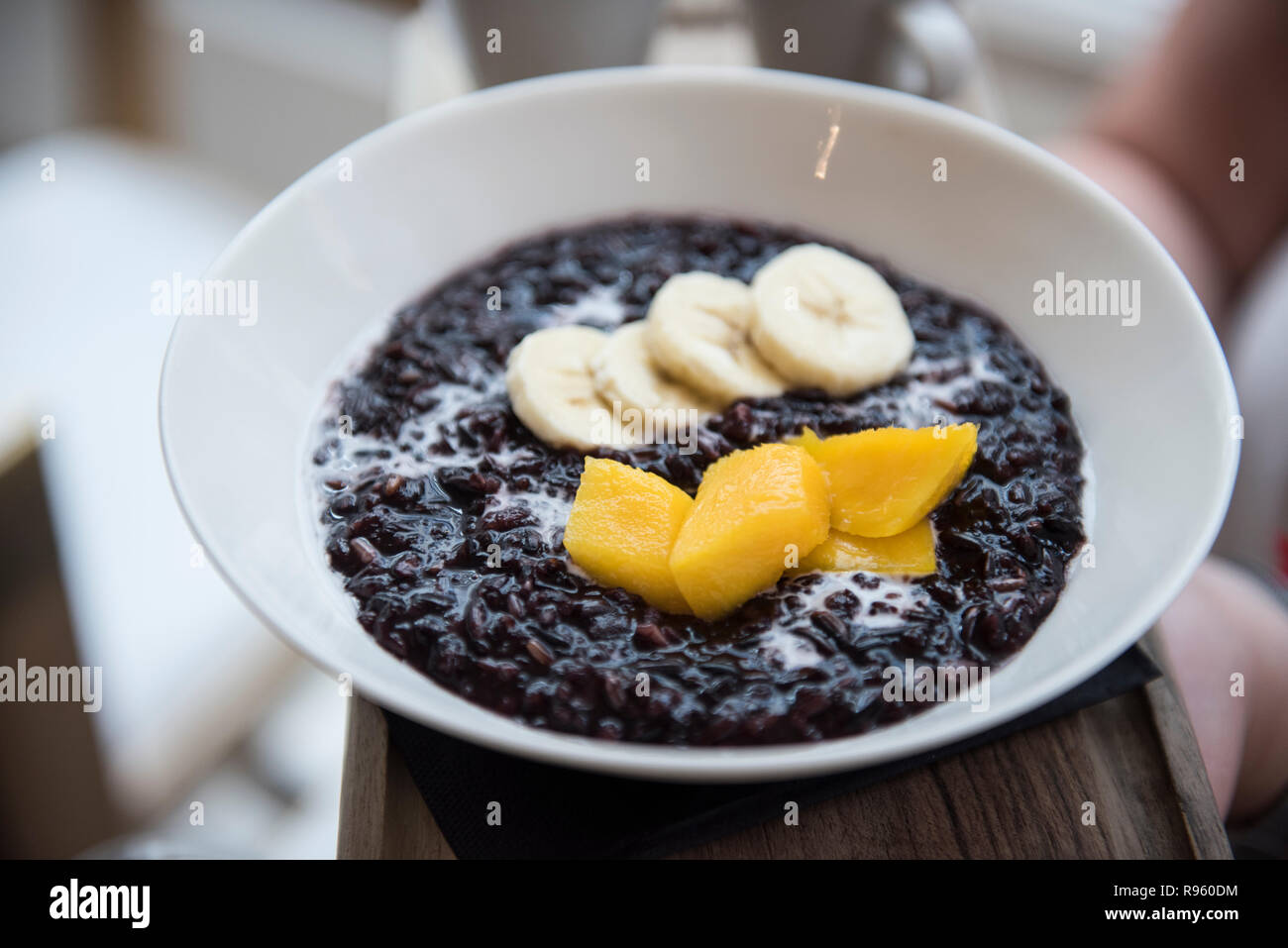 Image of very delicious and tastyblack rice, coconut milk, mango and banana is seen being sold at a restaurant in Spain. The food seems to be very del Stock Photo