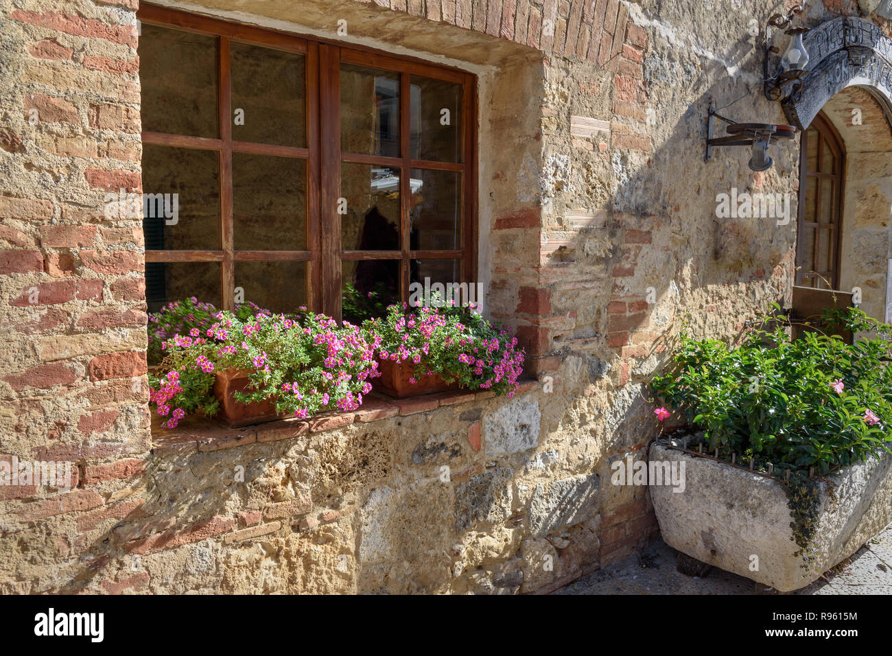 Old house decorated with flowers on sunny day in Monteriggioni, Tuscany ...