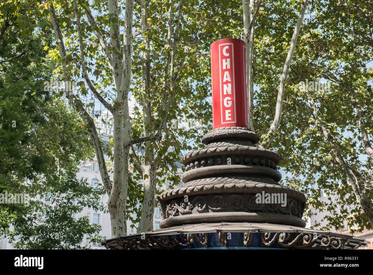 An old architectural pillar with a text signboard on it. The word Change is written on it. On the background, trees are seen along with the blue sky. Stock Photo