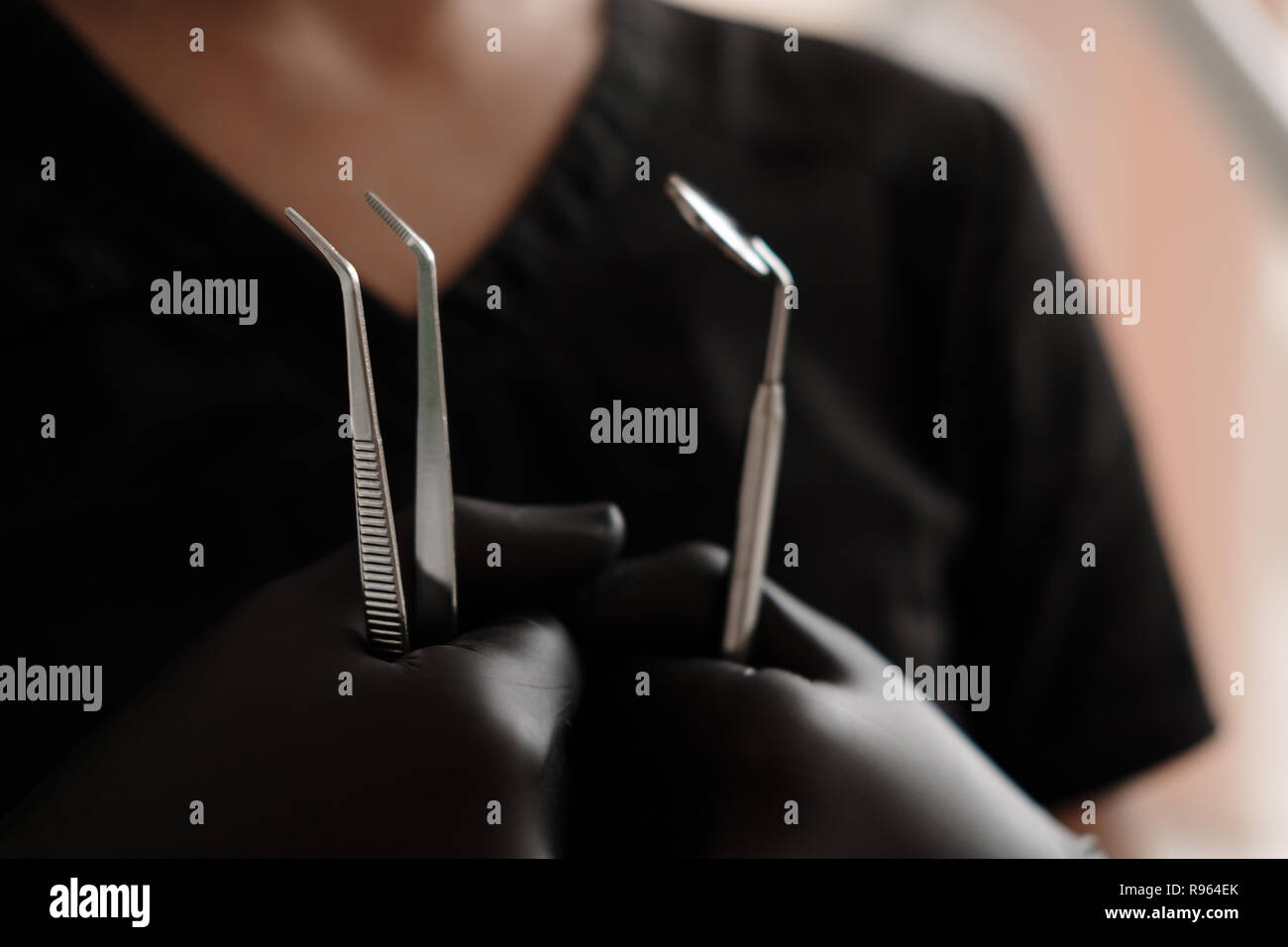 Dentist in black gloves and medical gown holding tools dental