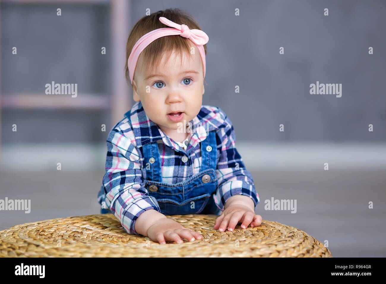 Portrait of a cute baby girl on a light background with a wreath ...