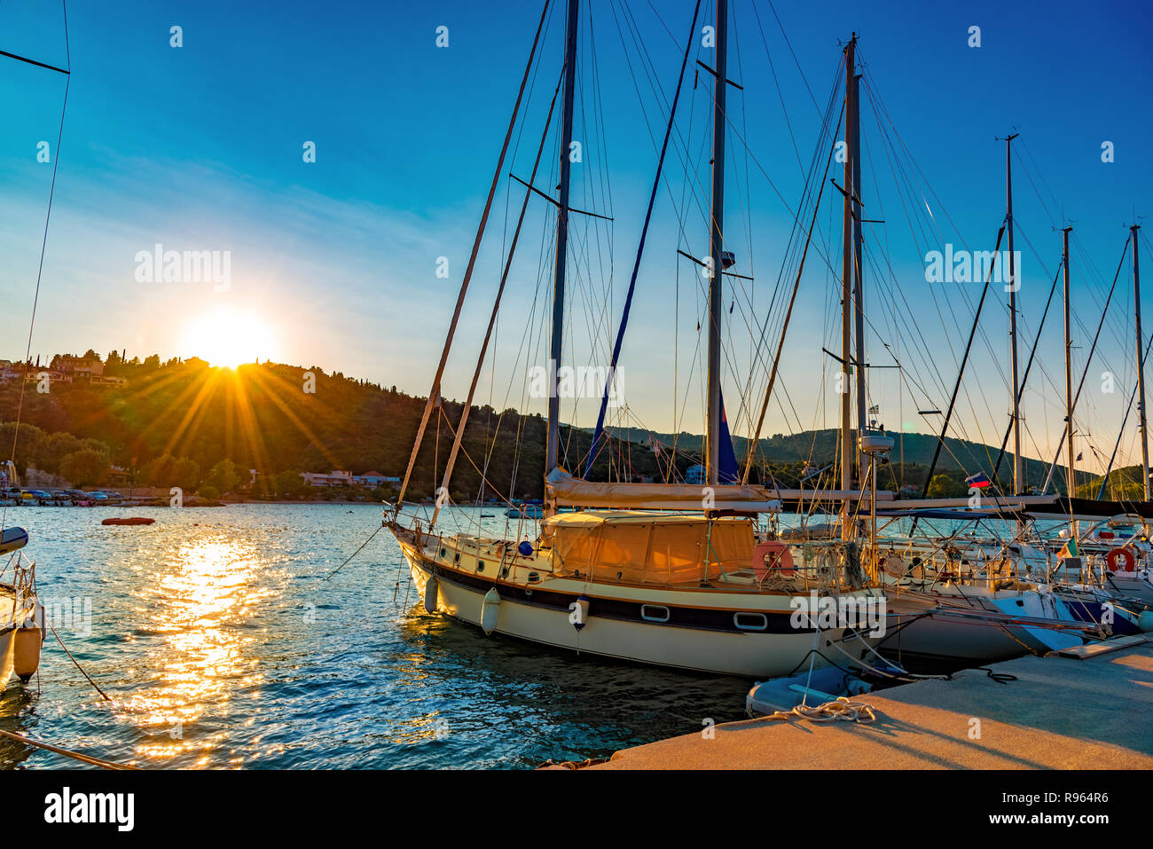 Beautiful sunrise over Nydri port, traditional Greek sailing boats illuminated by morning light in Lefkada island Stock Photo