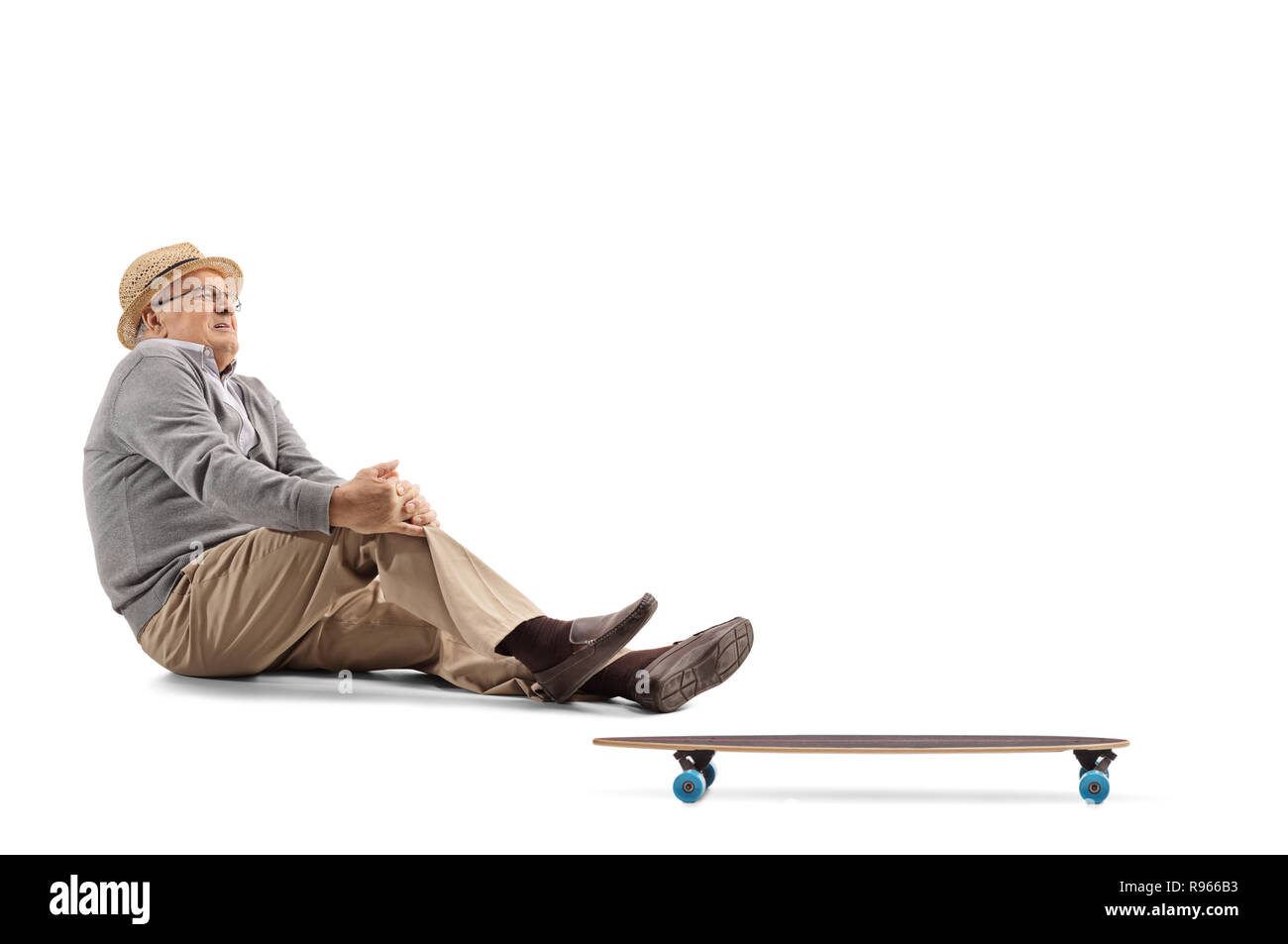 Elderly man in pain sitting on the floor next to a longboard and ...