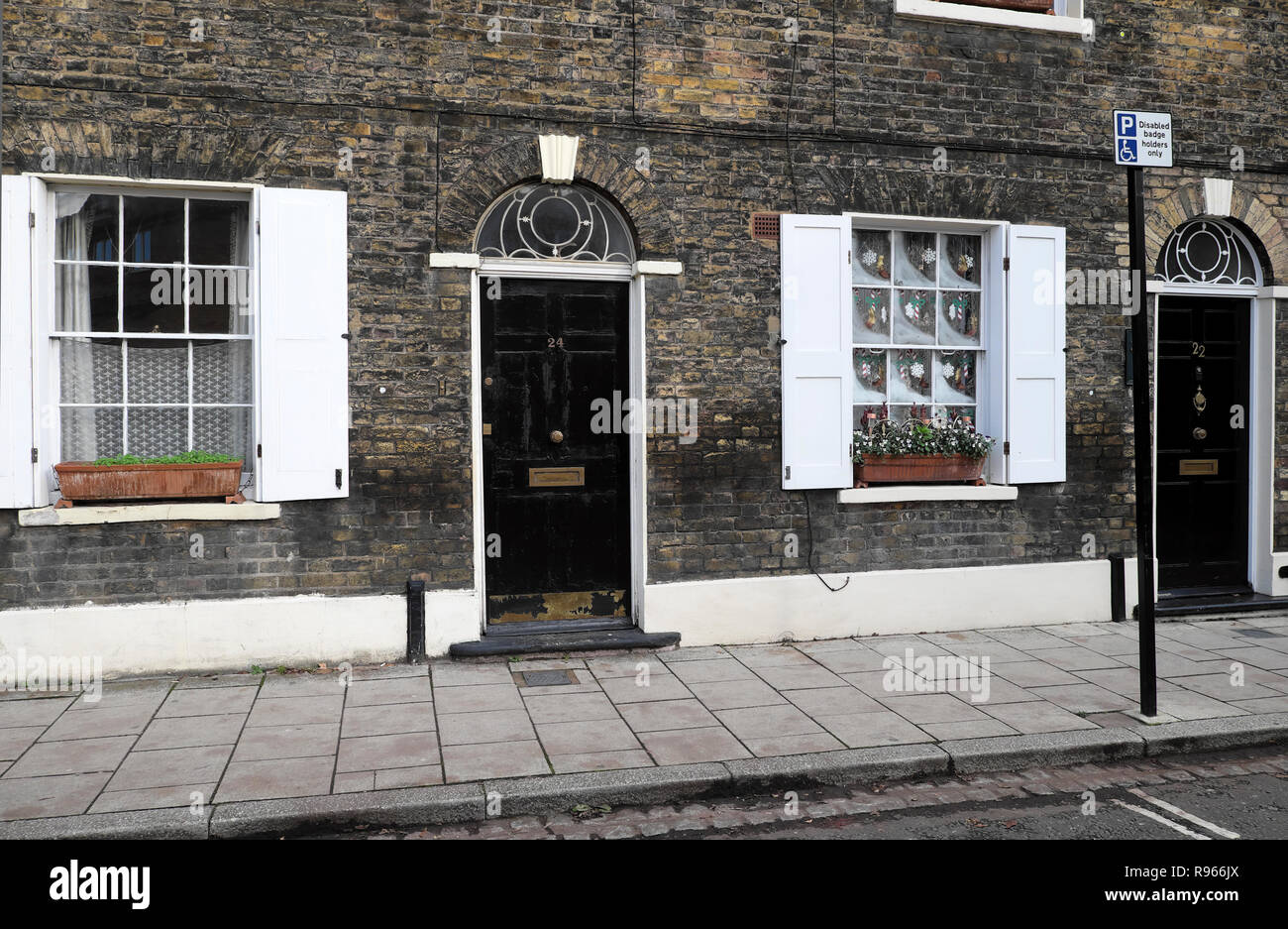 Christmas decorations and viola flowers in window box outside a house with black door, fanlight and shutters on window South London UK  KATHY DEWITT Stock Photo