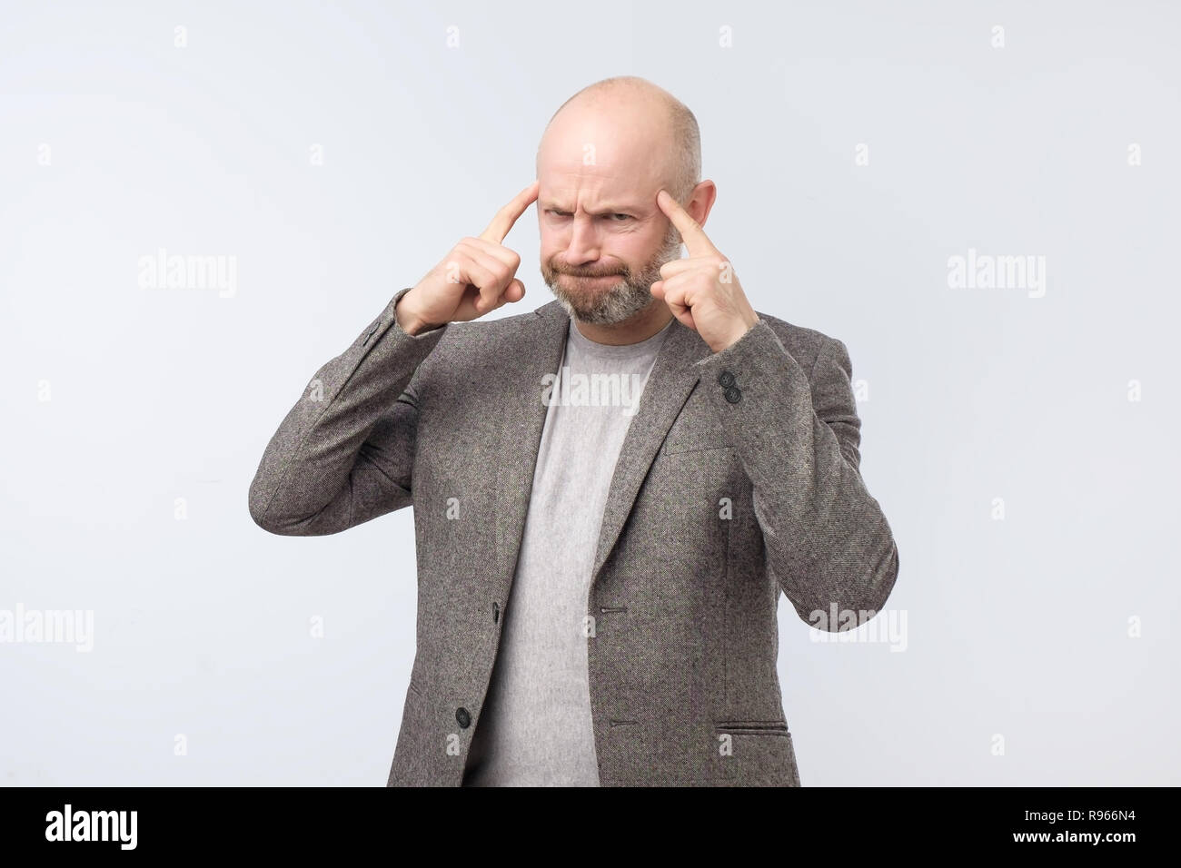 Angry tired european man gesturing with his finger against temple trying to remember something. Stock Photo
