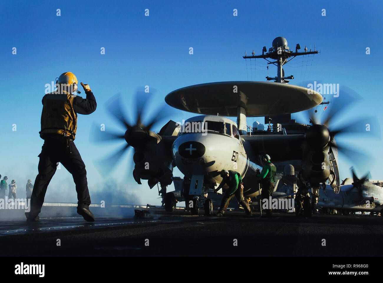 An aircraft flight deck director guides an E-2C Hawkeye assigned to the 'Golden Hawks' of Carrier Airborne Early Warning Squadron One One Two (VAW-112) onto a steam propelled catapult for launch off the flight deck of the Nimitz-class aircraft carrier USS John C. Stennis (CVN 74). U.S. Navy photo by Mass Communication Specialist 3rd Class Jon Hyde Stock Photo
