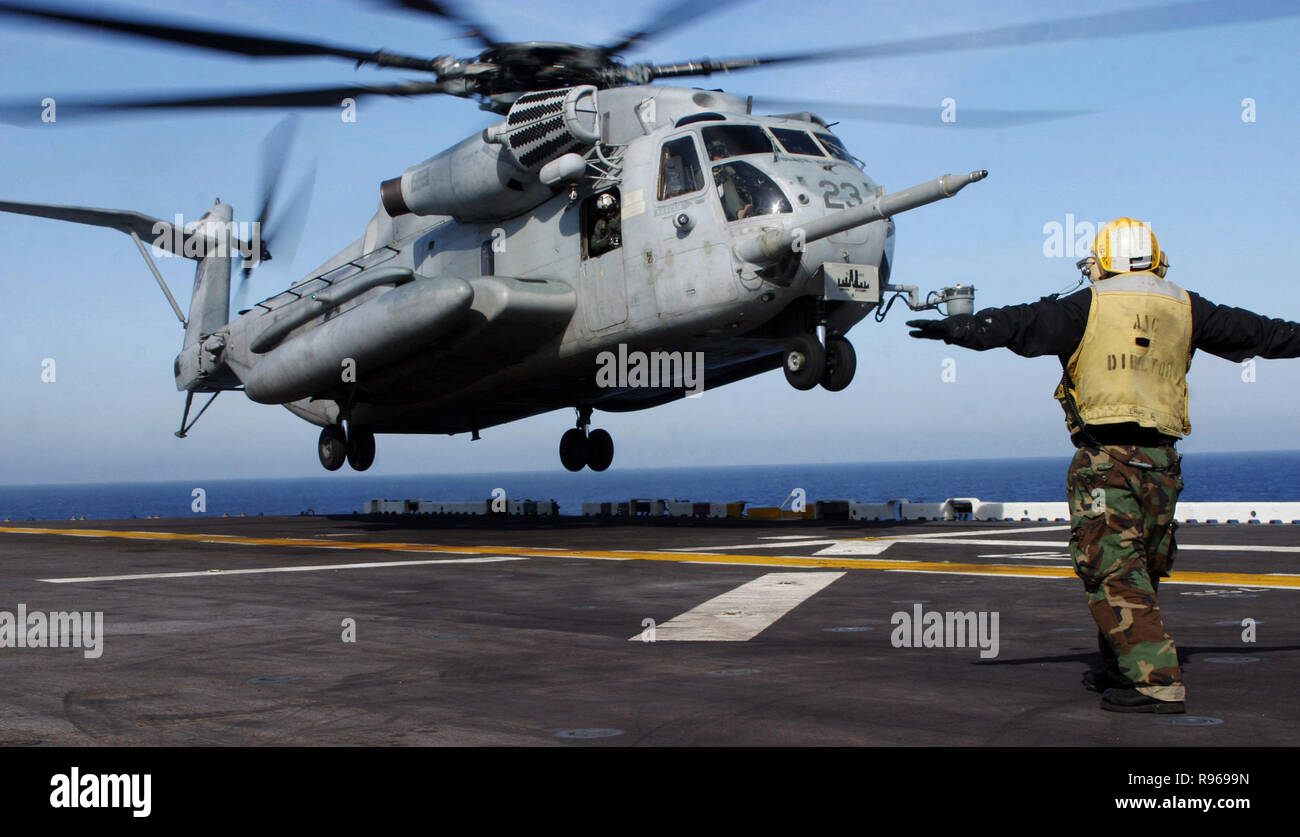 A sailor aboard amphibious assault ship USS Bataan (LHD 5), guides a CH-53E Super Stallion helicopter.U.S. Marine Corps photo by Sgt. Freddy G. Cantu Stock Photo
