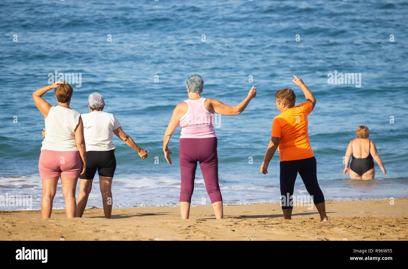 Elderly women stretching on beach during keep fit class in Spain Stock Photo