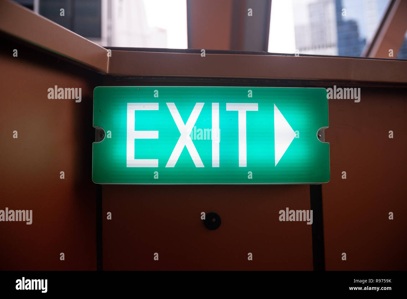 14.12.2018, Singapore, Republic of Singapore, Asia - An illuminated EXIT sign mounted to a wall at an outside area in the central business district. Stock Photo