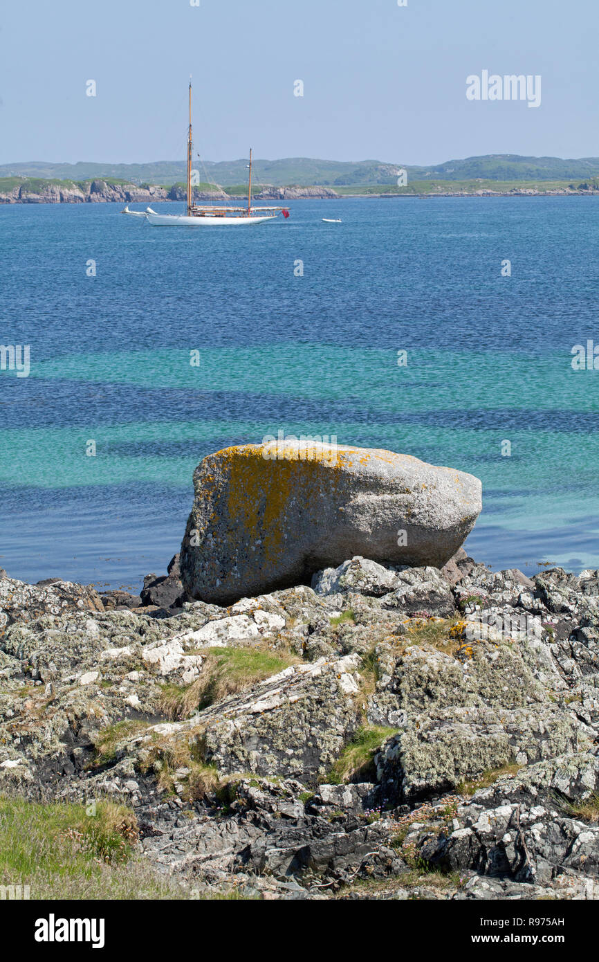 Moraine deposited, large boulder, granite, rock, stone, deposited, isolated foreground. Isle of Iona, Port Beag Na Sligineach, Sound of Iona, Inner Hebrides, Mull on the horizon. Argyll and Bute, west coast of Scotland. Stock Photo