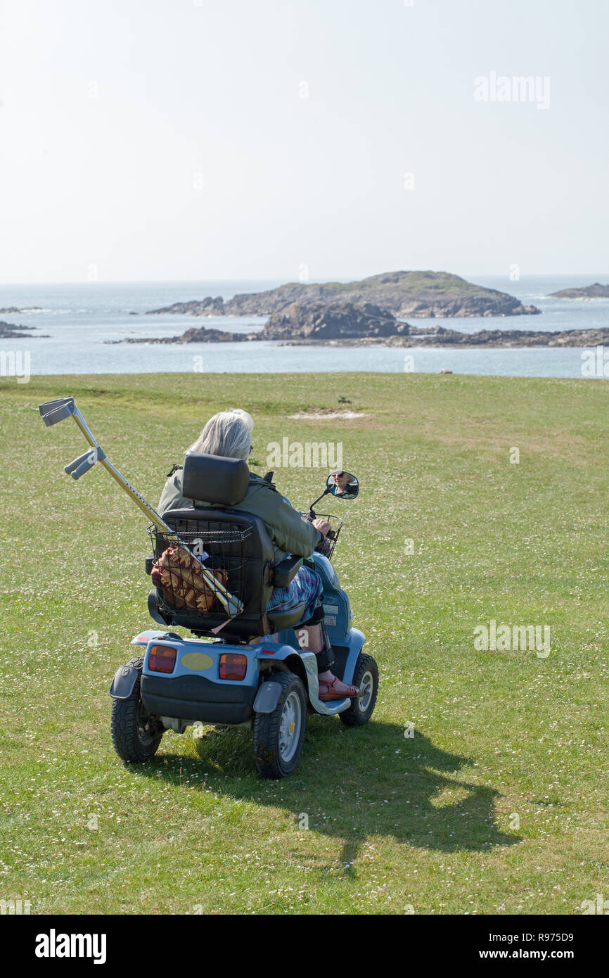 Access to a beach over A’ Machair and golf course, by electric ‘buggy’ for a physically impaired, disabled senior citizen to the Isle of Iona. The Inner Hebrides, Argyll and Bute. West coast of Scotland. Stock Photo