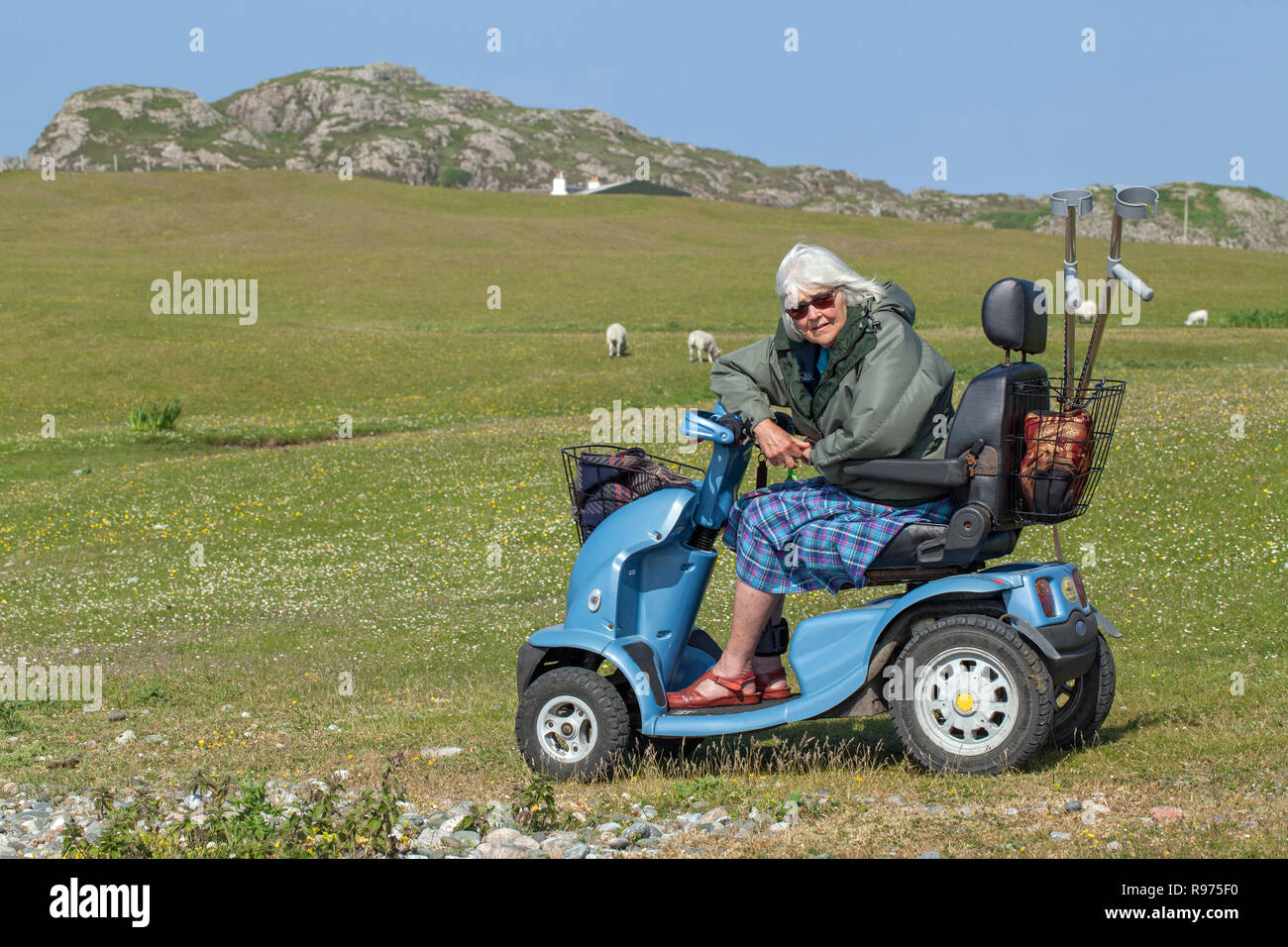 Disabled. Physically impaired. OAP. An elderly woman, driving a four-wheeled electric vehicle giving enjoyable independence and access to the rural scene, countryside and environment generally. Iona. The Inner Hebrides. Argyll and Bute, Scotland. Stock Photo