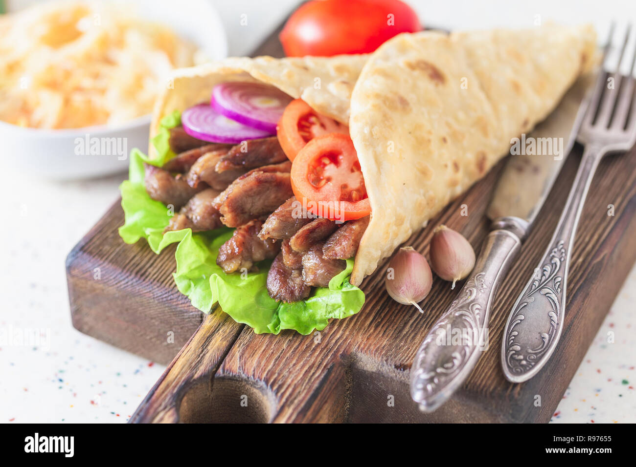 Handmade doner kebab is lying on the white table made of artificial ...