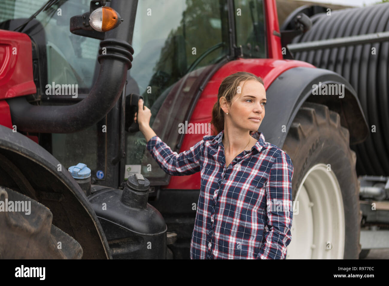 Agricultural worker standing next to a tractor in field Stock Photo