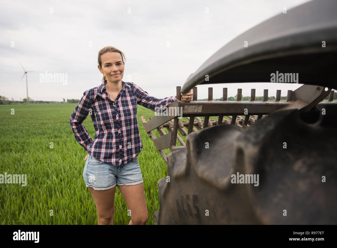 Agricultural worker standing next to a tractor in field Stock Photo
