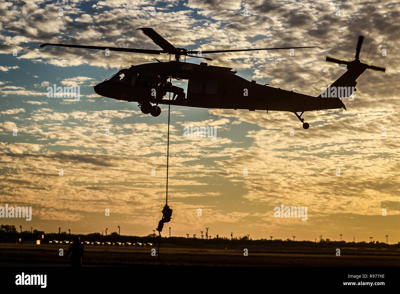 A silhouette of a UH-60 Blackhawk helicopter assigned to 2nd Assault  Helicopter Battalion, 82nd Combat Aviation Brigade, and Customs and Border  Protection (CBP) agents during a Fast Rope Extraction System (FRIES)  Training