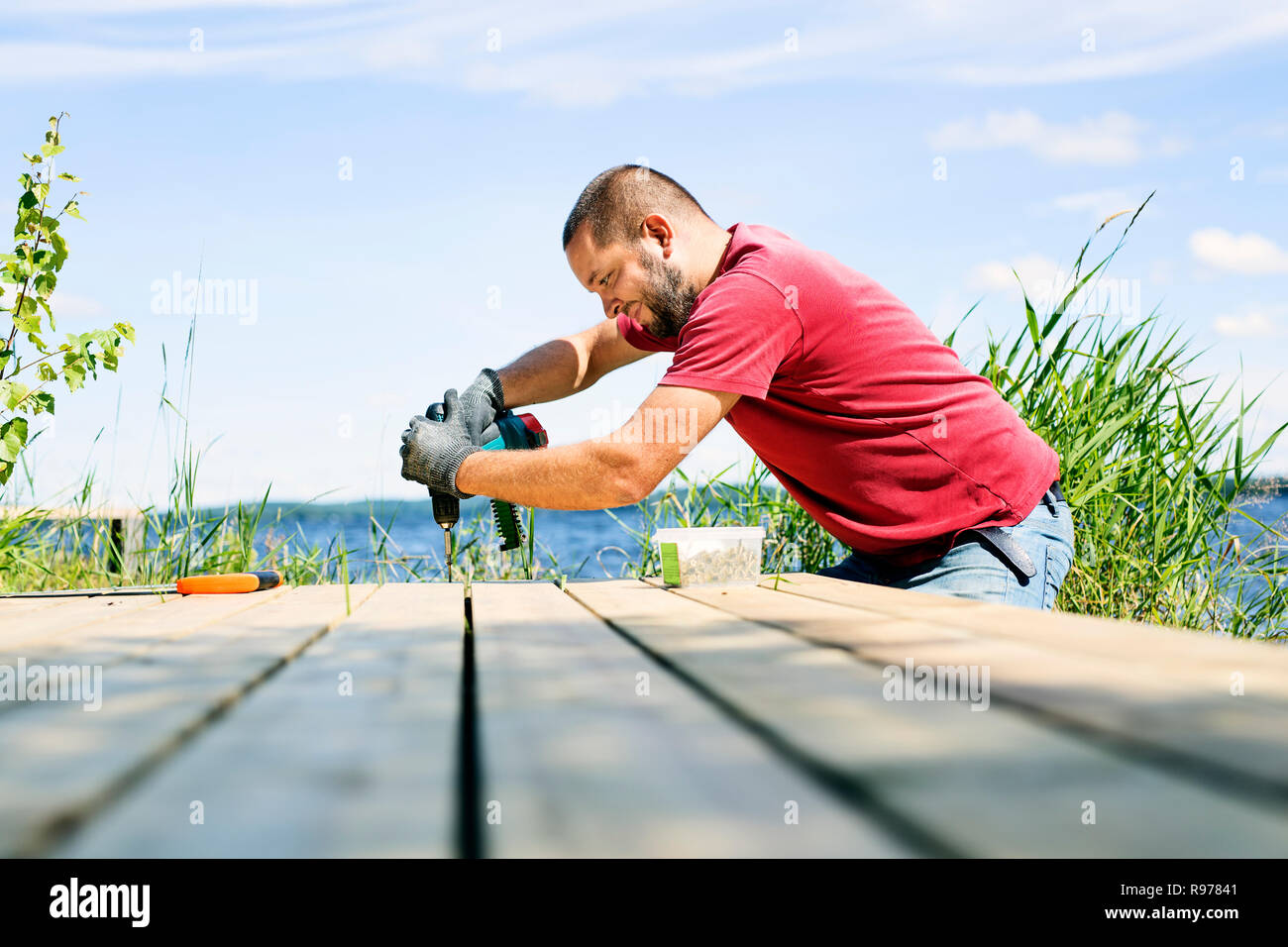 Mid adult man drilling a hole in a deck in Finland Stock Photo