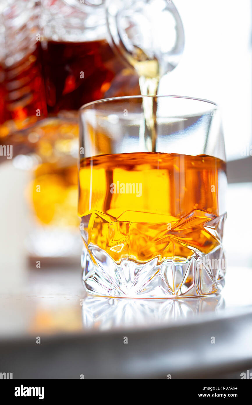 Whiskey in a tumbler alongside a cut glass decanter Stock Photo