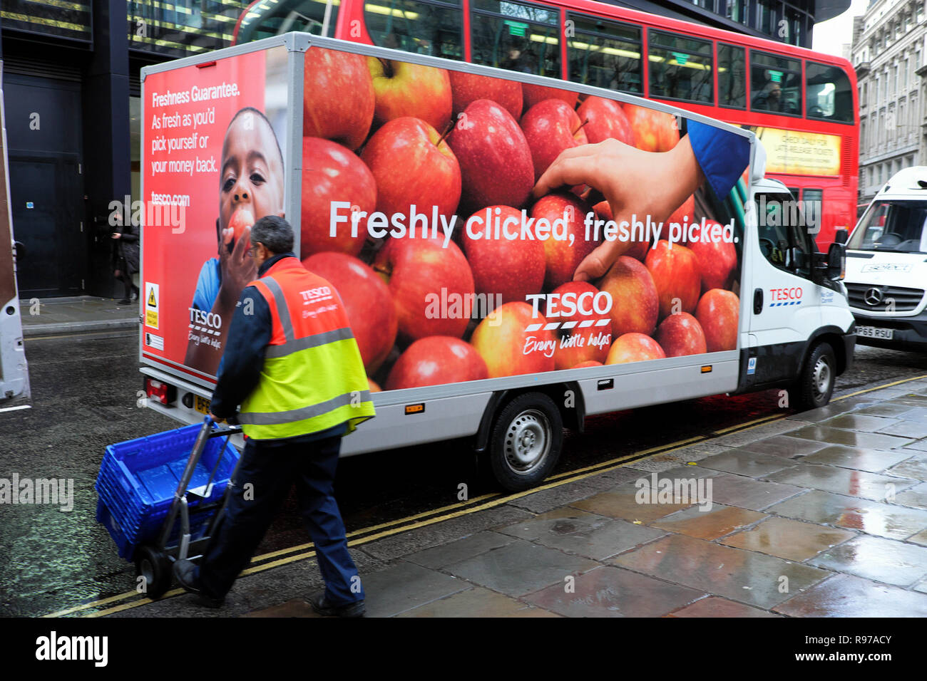 Tesco food delivery van and rear view of worker with apples online advert on side parked in Threadneedle Street in The City of London UK  KATHY DEWITT Stock Photo