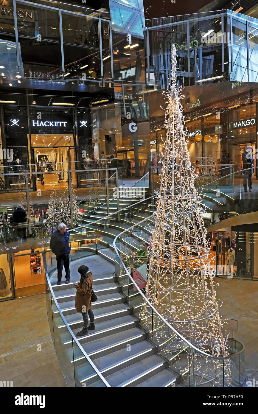 One New Change 2018 Christmas tree and shoppers on staircase inside interior building vertical view in London England UK  KATHY DEWITT Stock Photo