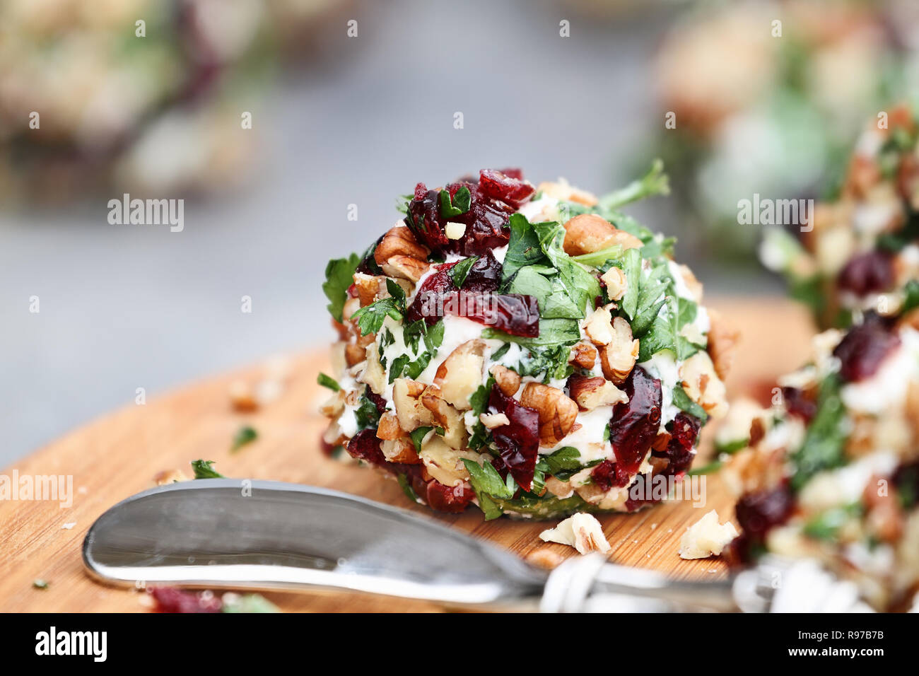 Cranberry nut cheese ball made with cream cheese, goat or feta cheese, parsley, cranberries and chopped pecans over a rustic background. Extreme shall Stock Photo