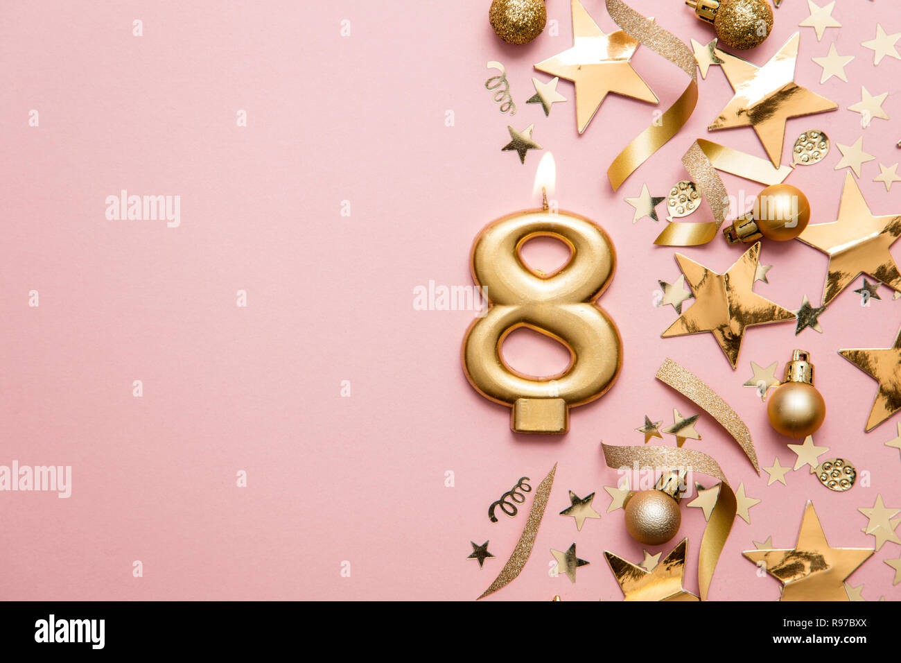 Number 8 gold celebration candle on star and glitter background Stock