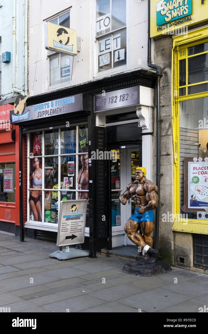Body Expert, a shop selling sports and fitness supplements, Northampton, UK; with a model of a muscled male bodybuilder by the door. Stock Photo